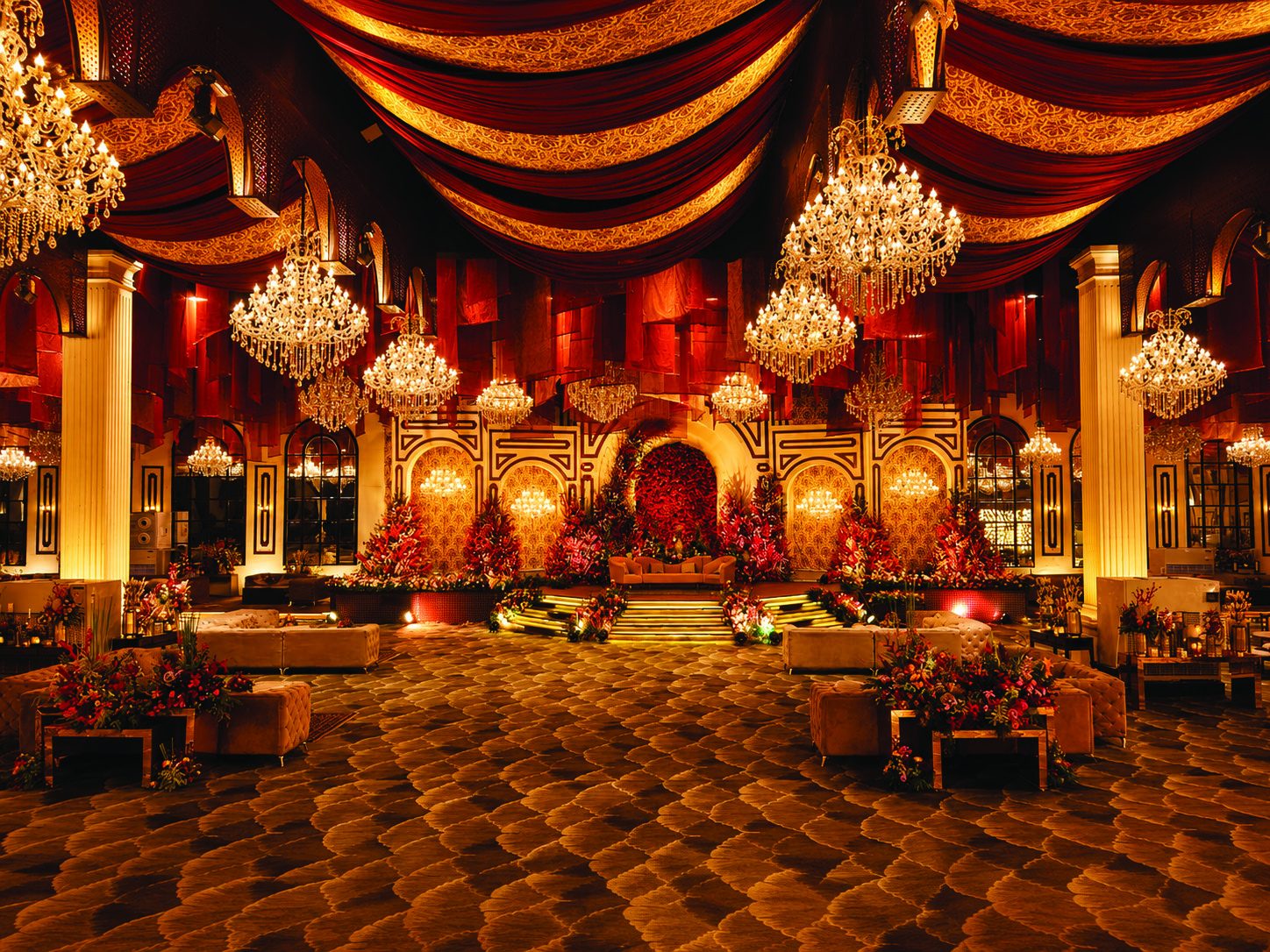 The Palace banquet hall with chandeliers and a floral stage